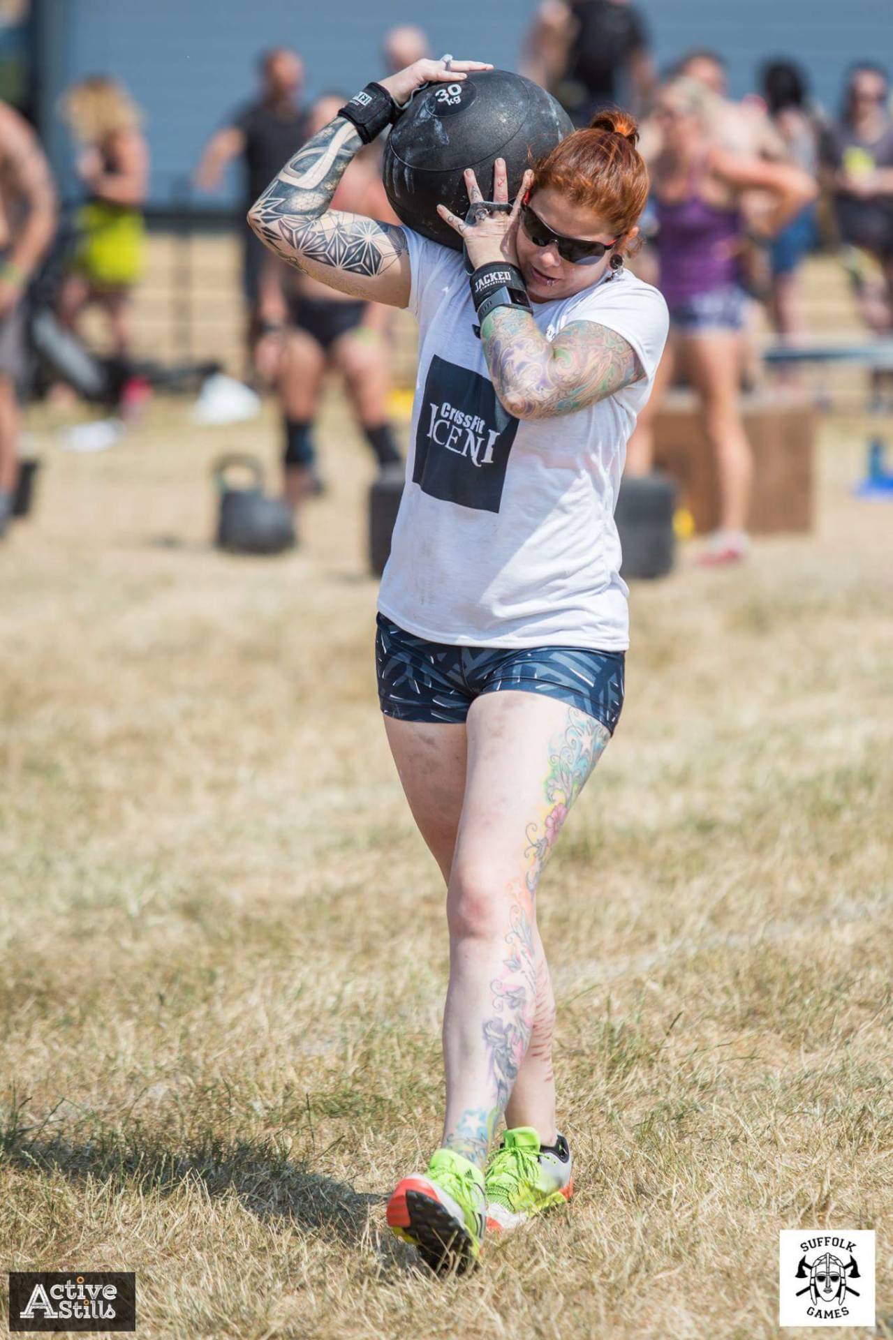 Phe carrying a heavy slam ball on her shoulder during a CrossFit competition.