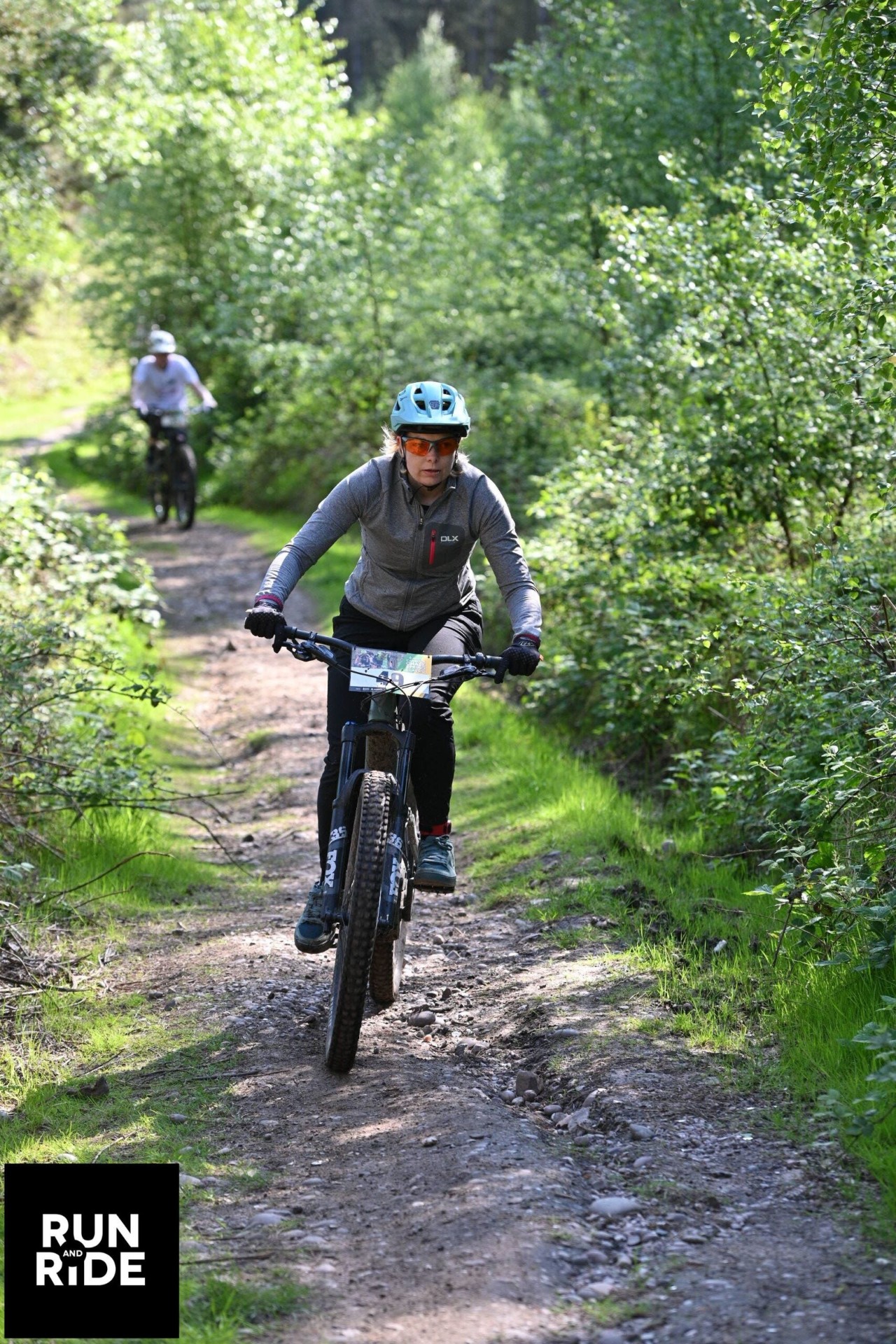 Phe riding a mountain bike along a narrow woodland trail in spring.