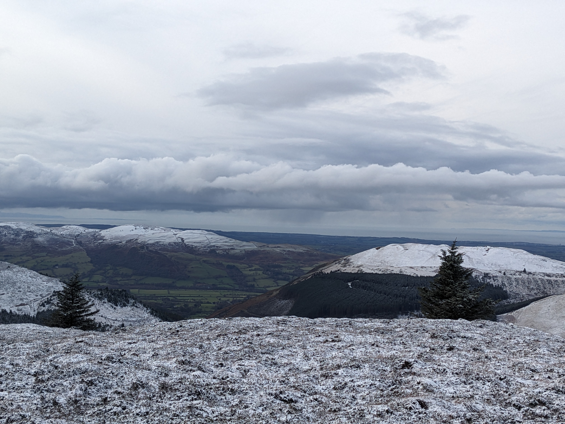 Snow-dusted hills under a low cloud bank, a calm winter landscape from one of Phe's walks.